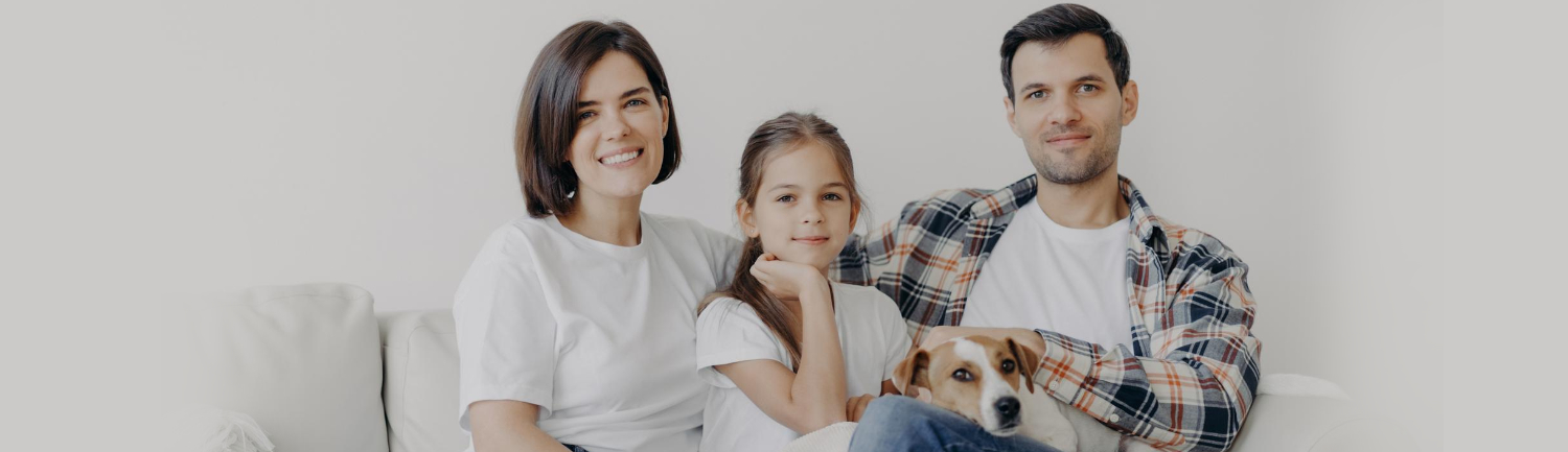 Happy family relaxing on a clean living room couch with their dog, enjoying a fresh and comfortable home after hardwood cleaning