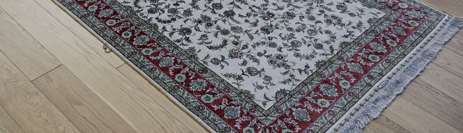 Detailed view of an elegant area rug lying on freshly cleaned hardwood floors, highlighting the contrast between rich rug patterns and smooth flooring after hardwood cleaning