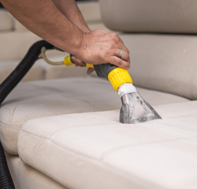 Residential upholstery cleaning on a light-colored sofa using steam extraction equipment, lifting dirt and moisture from fabric cushions for a deep, sanitized clean